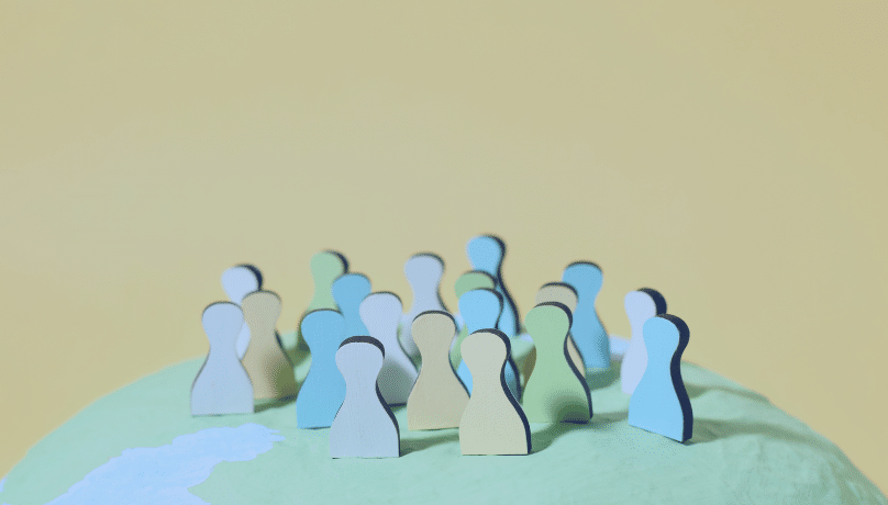 A diverse group of people stands on a globe, symbolizing Agile Development and Cultural Alignment in a global context. 